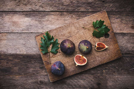 Cut Figs on chopping board and wooden table. Autumn season food photoの写真素材