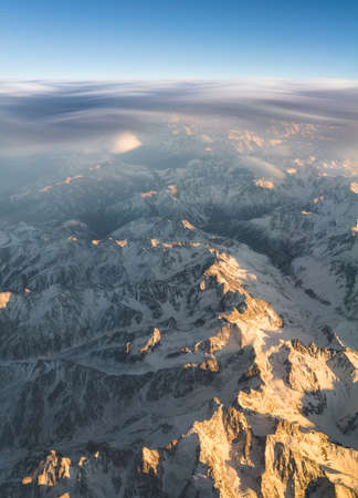 Mountains and clouds at sunset view from plane duting flight