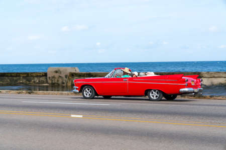 Red retro taxi car with tourists in Havana, Cuba. Captured on Malecon roadway in spring 2018のeditorial素材