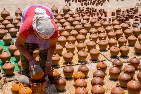 Woman glazing ceramic pots on Bhaktapur square. Captured in Nepal, Kathmandu valley in spring 2017