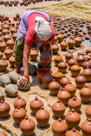 Woman glazing ceramic pots on Bhaktapur square. Captured in Nepal, Kathmandu valley in spring 2017のeditorial素材