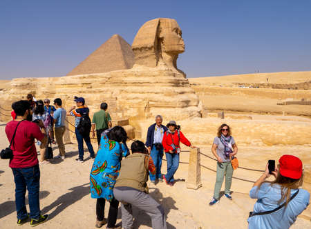 Tourists and Great Sphinx of Giza, with the Great Pyramid in the background. People take selfies. Cairo, autumn 2018のeditorial素材