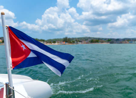 Cuba flag waving on boat at sea near Cuban coastline. Tourism in Cubaの写真素材