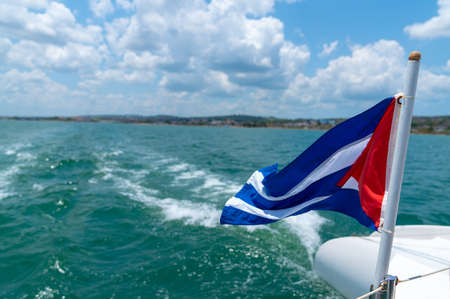 Cuba flag waving on boat at sea near Cuban coastline. Tourism in Cubaの写真素材