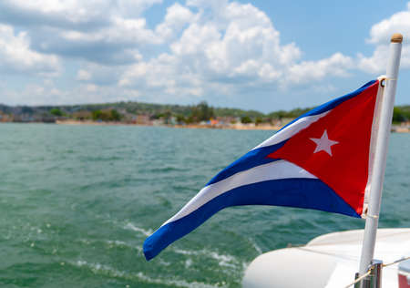 Cuba flag waving on boat at sea near Cuban coastline. Tourism in Cubaの写真素材