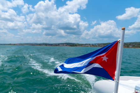 Cuba flag waving on boat at sea near Cuban coastline. Tourism in Cubaの写真素材