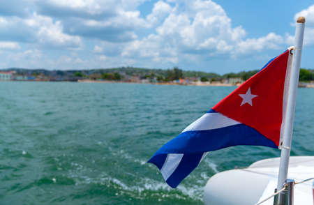 Cuba flag waving on boat at sea near Cuban coastline. Tourism in Cubaの写真素材