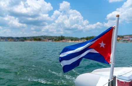 Cuba flag waving on boat at sea near Cuban coastline. Tourism in Cubaの写真素材