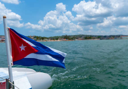 Cuba flag waving on boat at sea near Cuban coastline. Tourism in Cubaの写真素材