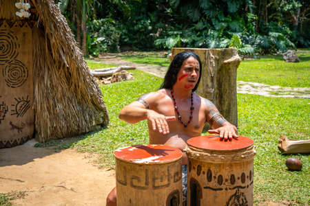 Man performing for tourists as Taino indian near Indian Cave orÂ Cueva del Indio in Vinales, Cuba. Spring 2019. Playing drums and singing songsのeditorial素材