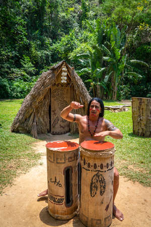 Man performing for tourists as Taino indian near Indian Cave orÂ Cueva del Indio in Vinales, Cuba. Spring 2019. Playing drums and singing songsのeditorial素材
