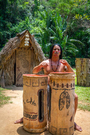 Man performing for tourists as Taino indian near Indian Cave orÂ Cueva del Indio in Vinales, Cuba. Spring 2019. Playing drums and singing songsのeditorial素材