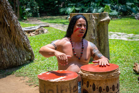 Man performing for tourists as Taino indian near Indian Cave orÂ Cueva del Indio in Vinales, Cuba. Spring 2019. Playing drums and singing songsのeditorial素材
