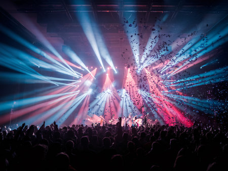 Energetic crowd enjoying a vibrant concert with colorful lights and confetti raining down.の素材
