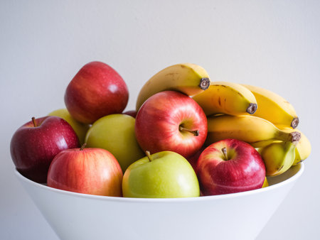 A vibrant bowl filled with fresh red and green apples alongside ripe bananas.の素材