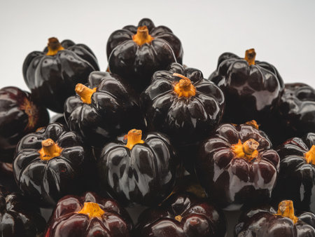A pile of glossy black eggplants with bright orange stems, showcasing their vibrant colors and unique shapes.の素材