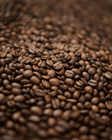 Close-up of a rich collection of roasted coffee beans on a textured surface.の素材