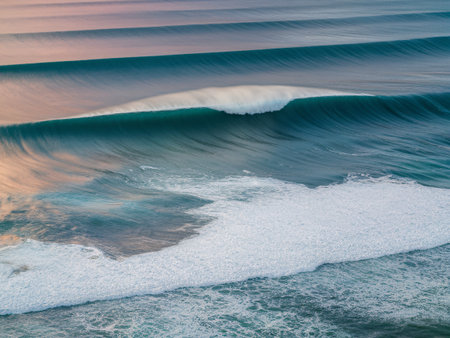 Majestic turquoise waves gently rolling onto the shore at sunset, creating a serene coastal atmosphere.の素材