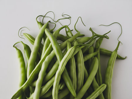 Fresh green beans arranged artistically on a white background.の素材
