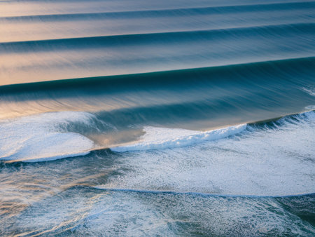 Stunning aerial view of turquoise ocean waves rolling towards a serene shoreline.の素材