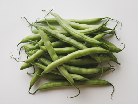 Fresh green beans piled on a white surface.の素材