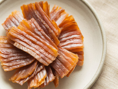 A beautifully arranged plate of dried fish slices, showcasing a rich orange-brown hue and texture.の素材