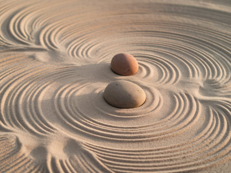 Two smooth stones surrounded by intricate patterns in fine sand, creating a tranquil scene.の素材