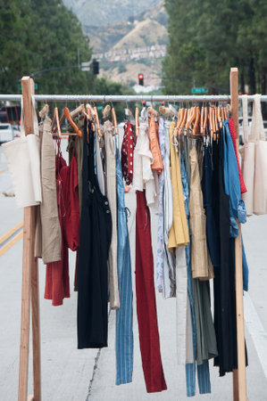 Garage sale concept â various clothes hanging on a clothing rack in the streetの写真素材