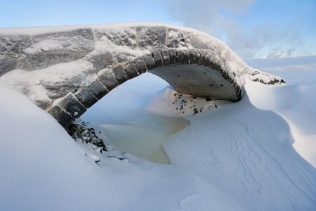 Small old stone bridge in snowy winter dayの写真素材
