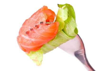 Roll of salmon with leaf of lettuce on a forkの写真素材