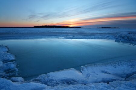 Early morning dawn with snow and refrozen waterの写真素材