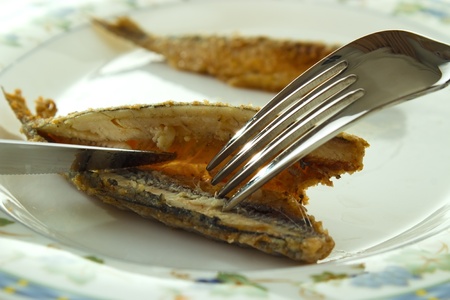  *** Local Caption *** Cleaning cooked fish (fried vendace, small freshwater whitefish) for eating with fork and knifeの写真素材