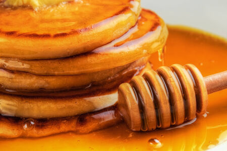 Honey with wooden drizzler and pancakes closeupの写真素材