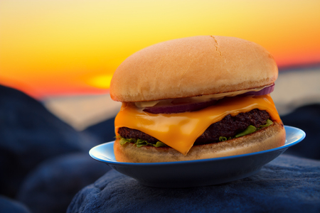 Cheese burger on beach rock in evening sunsetの写真素材
