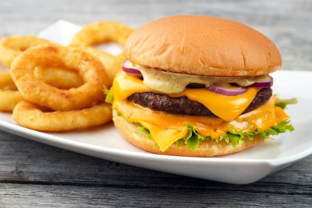Cheeseburger served with deep fry onion rings on the white square dishの写真素材