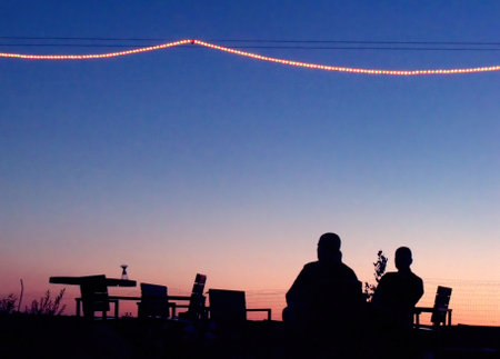 Cozy summer evening, two friends spending time together on a roof bar silhouette