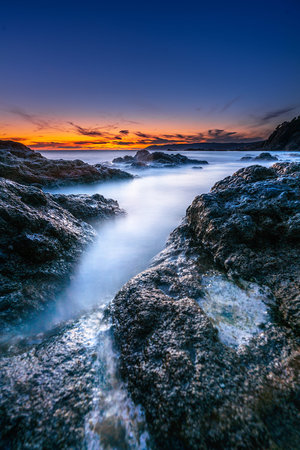Colorful sunset on a rocky beach of the Ligurian Sea, Rosignano Marittimo, Livorno, Tuscany, Italy.