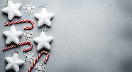A vertical arrangement of white star ornaments, red and white striped candy canes, and delicate snowflake decorations on a textured gray surface, evoking a festive holiday spirit.の素材
