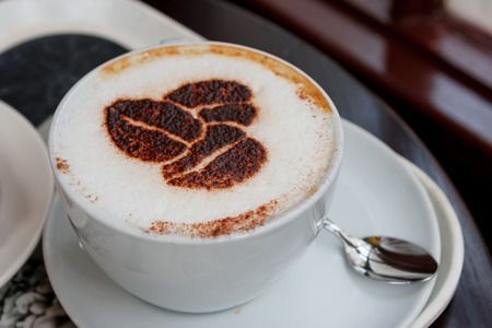 Cup of cappuccino with coffee beans shaped designの写真素材