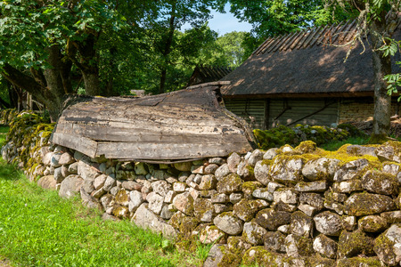 Mossy stone fence and old boat as decoration. Koguva village, Saaremaa island, Estonia, Europeのeditorial素材