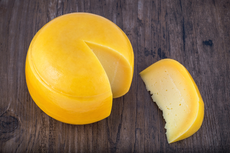 Cheese head with a slice cut off on wooden table. Selective focusの写真素材