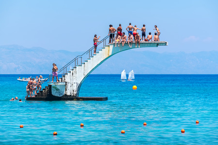 RHODES, GREECE - JULY 4, 2015: Many people having fun on diving board at Elli Beach, the main beach...