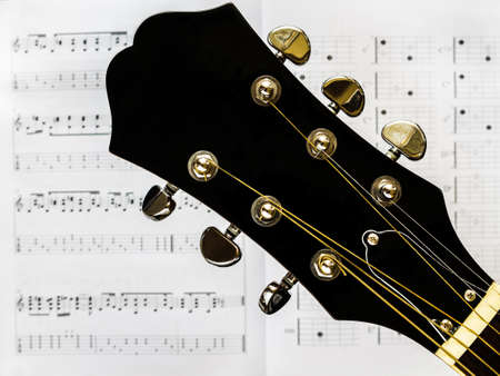 Acoustic guitar - head and tuning keys. A musical instrument. Acoustic guitar and notes.