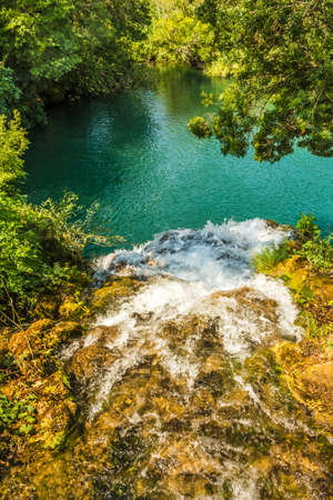 View from above the waterfall. Water falling into the green lake. A lake among trees in Krka pitch in Croatia.の写真素材