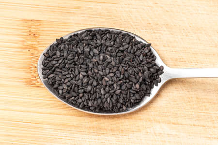 Grains of black sesame on a wooden chopping board. Additives to eat - sesame seeds. Healthy food....