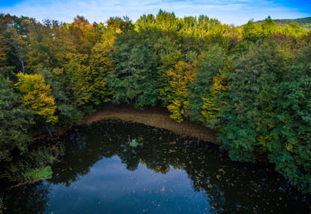 Aerial landscape. Wild lake in the autumn forest in the shadow of the hill.の写真素材