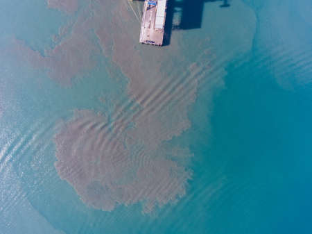 Aerial view of the dirt in the water near the pier at the port.