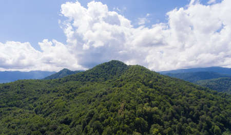 Aerial view. Summer mountain landscape. Forested mountains and clouds.