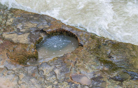 A small cave in the river carved the rocky shore.