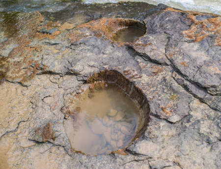 Holes in the rocky bank of a mountain river.の写真素材
